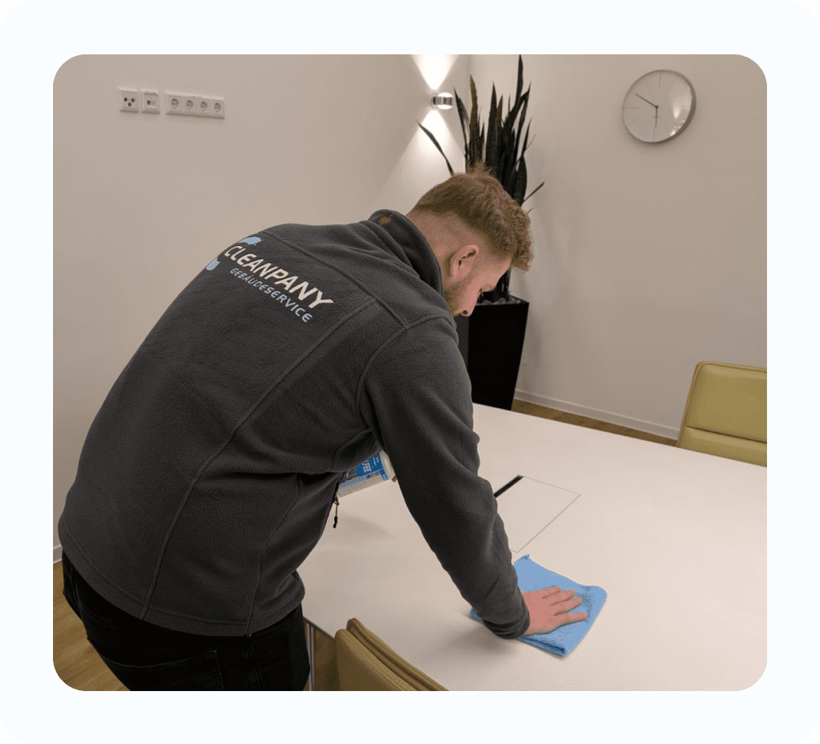 Reinigungskraft führt eine Gebäudereinigung im Flurbereich mit einem Bodenwischer durch.
