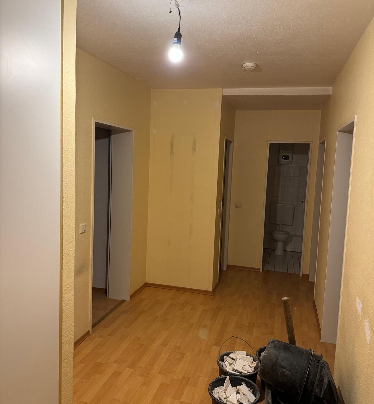 Leerer Wohnungsflur nach einer Entrümpelung mit geräumten Räumen und sauberem Boden.