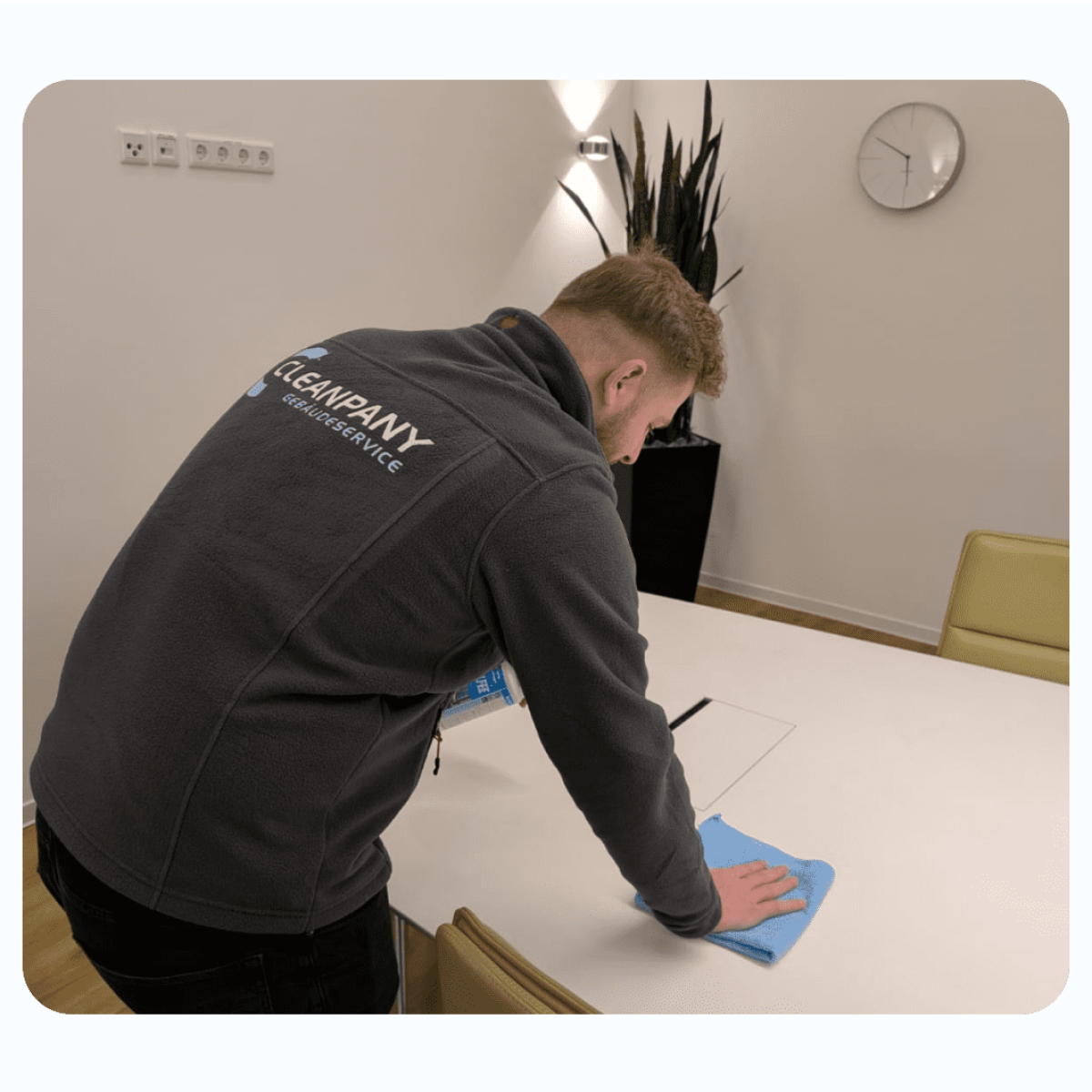 Reinigungskraft führt eine Gebäudereinigung im Flurbereich mit einem Bodenwischer durch.